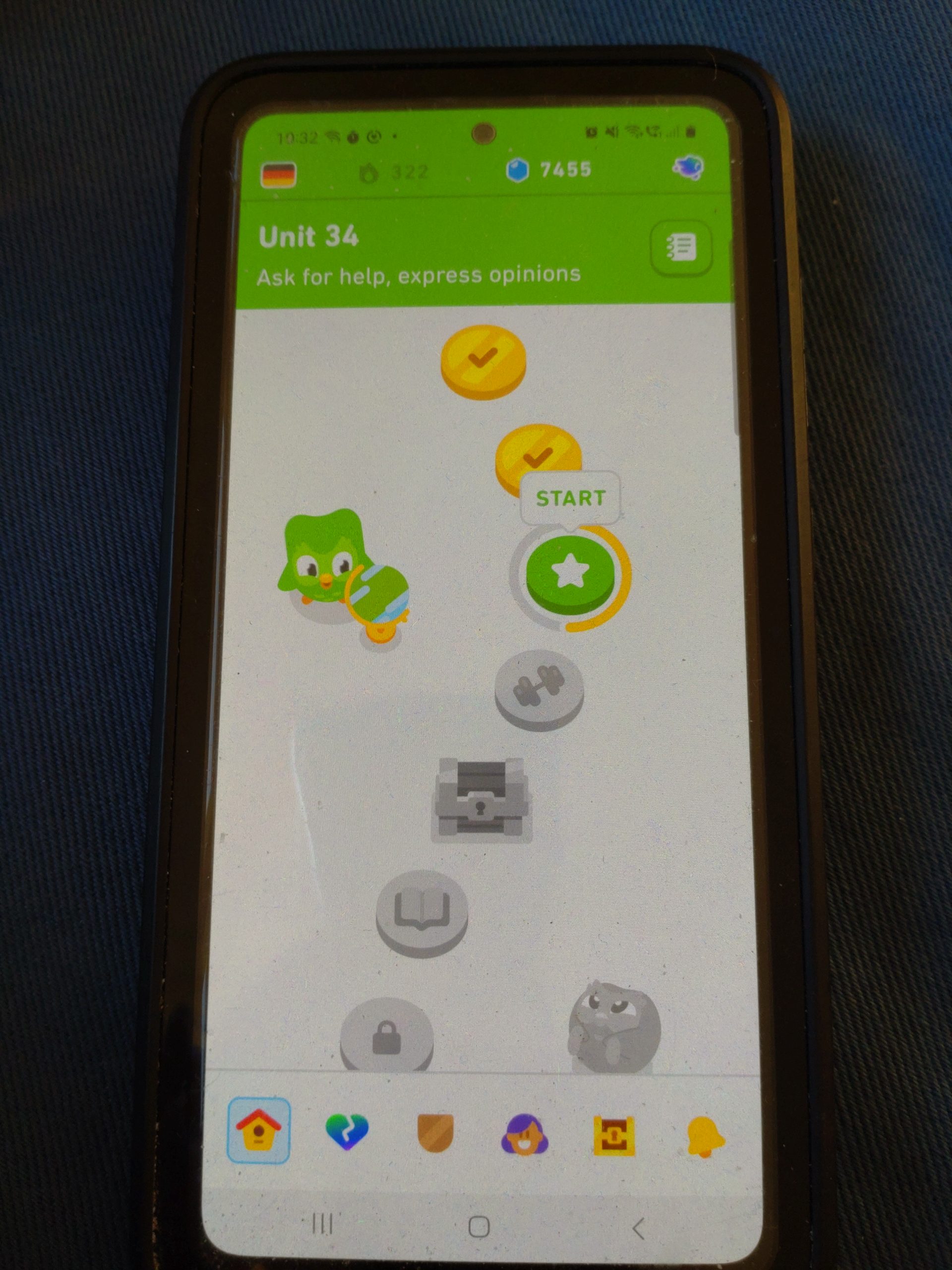 A phone to show the front page of a Duolingo language learning app. There are some circles coloured in gold and others grey.