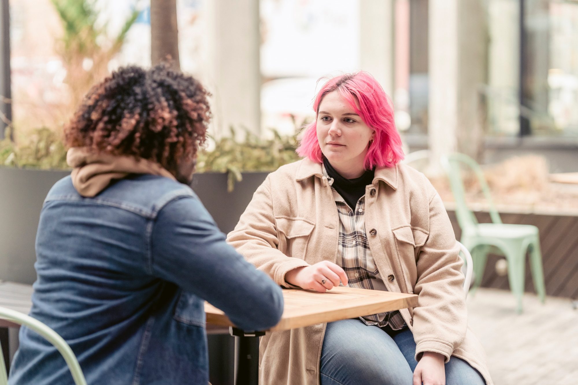 Two people outside sitting a a table and talking